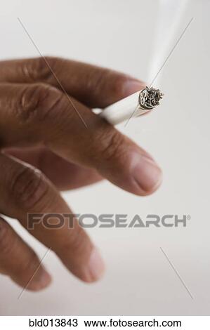 Stock Image - Close up of hand holding cigarette . Fotosearch