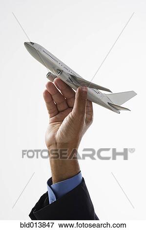 Stock Photo - Close up of hand holding toy airplane in air . Fotosearch