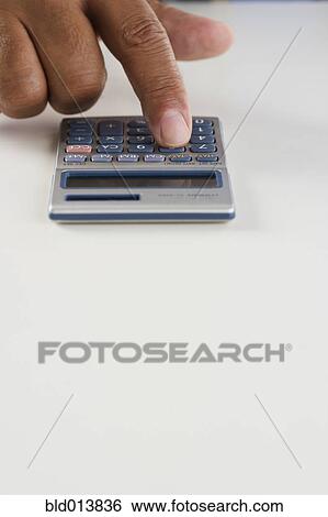 Stock Photograph - Close up of hand using calculator. Fotosearch