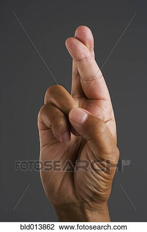 Stock Image - Close up of hand with fingers crossed. Fotosearch
