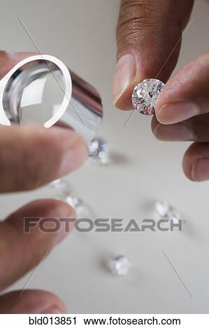 Stock Image - Close up of hands examining diamonds . Fotosearch