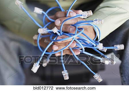 Stock Image - Close up of hands holding Ethernet cables. Fotosearch