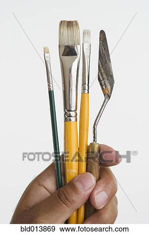 Close up of hands holding paintbrushes and palette knife View Large Photo Image Stock Photo - Close up of hands holding paintbrushes and palette knife. Fotosearch