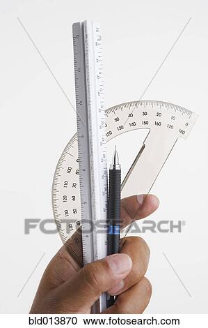 Stock Image - Close up of hands holding ruler and protractor. Fotosearch