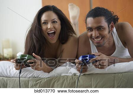 Couple laying on bed playing video games View Large Photo Image Stock Image - Couple laying on bed playing video games. Fotosearch