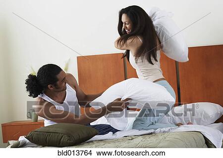 Picture - Couple pillow fighting in bed. Fotosearch