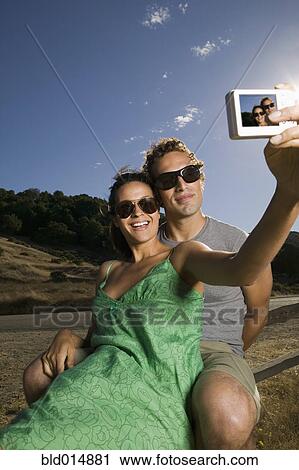 Stock Image - Couple taking self-portrait with camera. Fotosearch