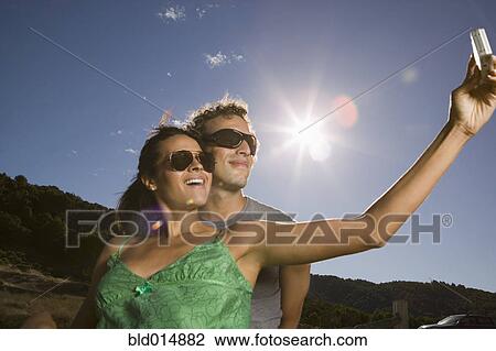 Stock Image - Couple taking self-portrait with camera. Fotosearch