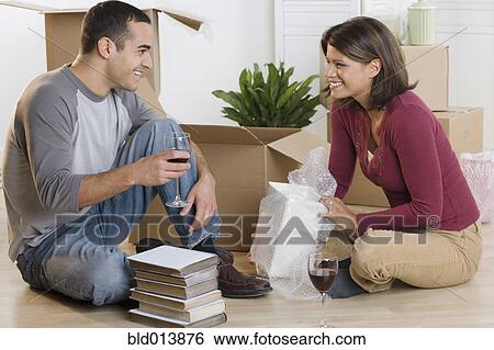 Couple unpacking boxes and drinking wine View Large Photo Image Stock Photograph - Couple unpacking boxes and drinking wine. Fotosearch