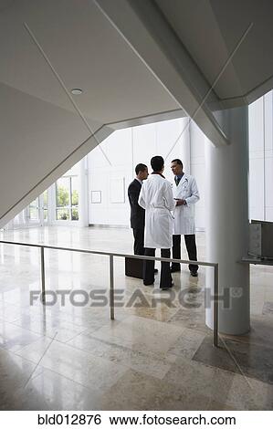 Doctors conferring with businessman View Large Photo Image Stock Photograph - Doctors conferring with businessman. Fotosearch