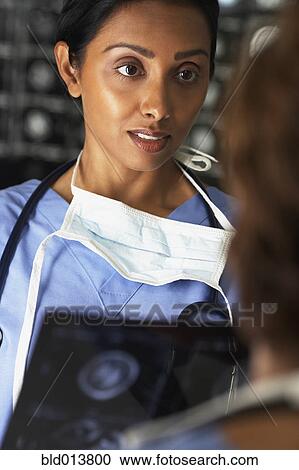 Stock Image - Female doctor looking at x-rays. Fotosearch