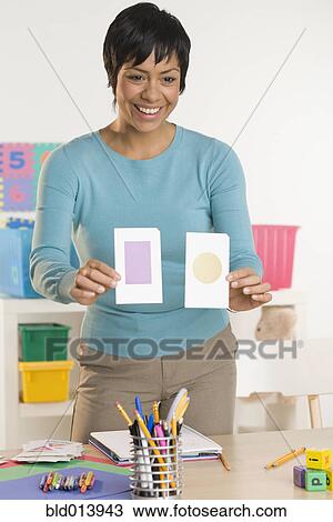 Stock Image - Female teacher holding up flash cards. Fotosearch