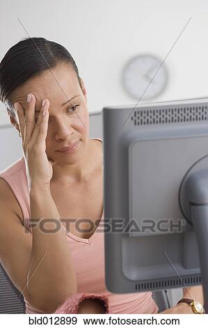 Stock Photo - Frustrated woman looking at computer with hand on face. Fotosearch