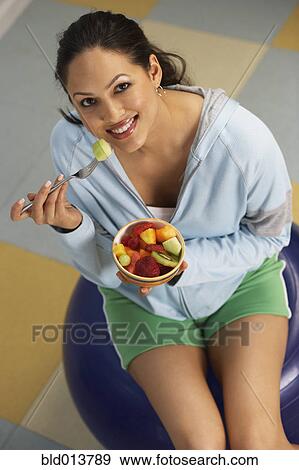High angle portrait of woman eating bowl of fruit View Large Photo Image Stock Photo - High angle portrait of woman eating bowl of fruit. Fotosearch