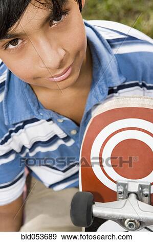 Hispanic boy holding skateboard View Large Photo Image Stock Photo - Hispanic boy holding skateboard. Fotosearch