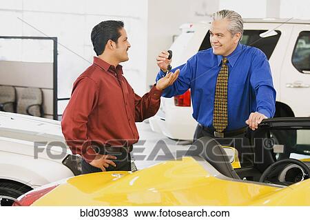 Hispanic car salesman handing car keys to buyer View Large Photo Image Stock Image - Hispanic car salesman handing car keys to buyer. Fotosearch