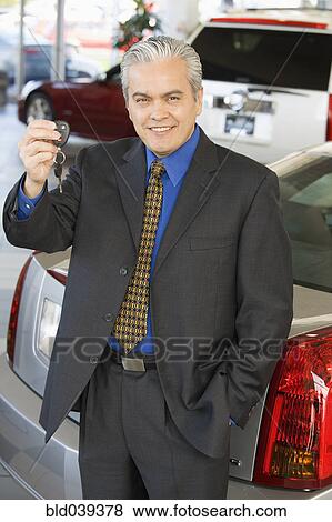 Stock Photo - Hispanic car salesman holding car keys. Fotosearch