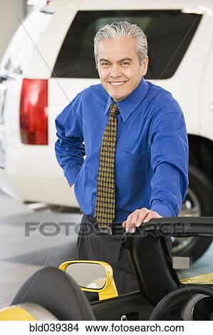 Hispanic car salesman leaning on new car View Large Photo Image Picture - Hispanic car salesman leaning on new car. Fotosearch