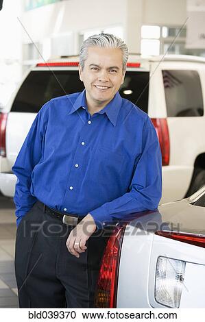 Hispanic car salesman leaning on new car View Large Photo Image Stock Image - Hispanic car salesman leaning on new car. Fotosearch