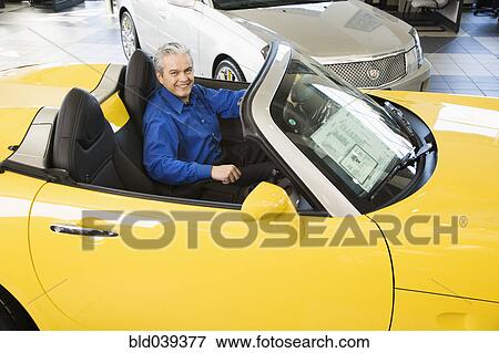 Stock Photo - Hispanic car salesman sitting in new car. Fotosearch