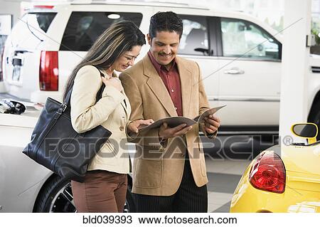 Stock Image - Hispanic couple at car dealership. Fotosearch