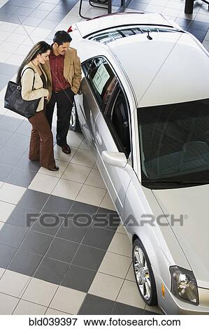 Stock Photo - Hispanic couple looking at new car. Fotosearch