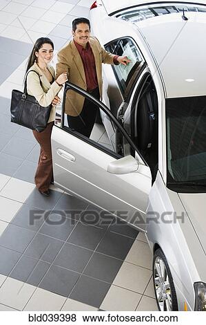 Hispanic couple looking at new car View Large Photo Image Stock Photo - Hispanic couple looking at new car. Fotosearch