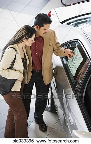 Stock Photograph - Hispanic couple looking at new car. Fotosearch