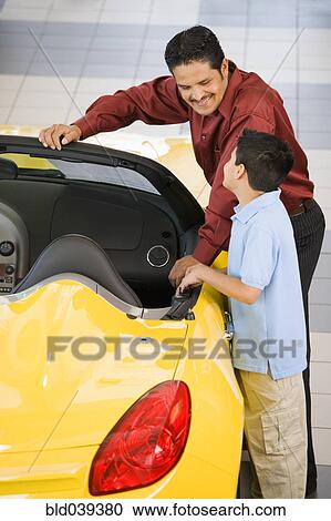 Stock Image - Hispanic father and son looking at new car. Fotosearch