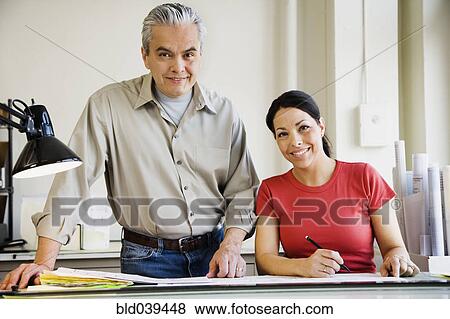 Stock Photo - Hispanic male and female architects with blueprints. Fotosearch