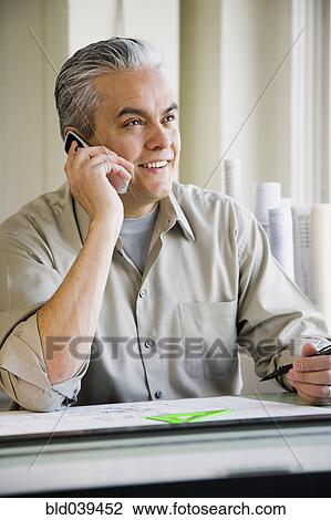 Stock Image - Hispanic male architect talking on cell phone. Fotosearch
