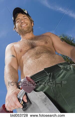 Hispanic man holding skateboard View Large Photo Image Stock Photo - Hispanic man holding skateboard. Fotosearch