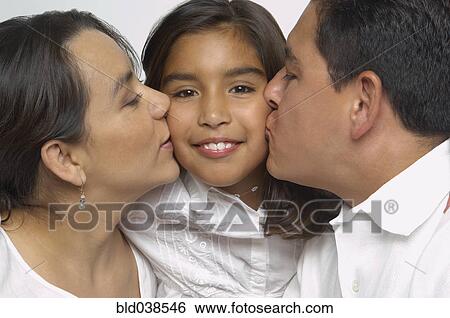 Stock Photograph - Hispanic parents kissing daughter's cheeks. Fotosearch