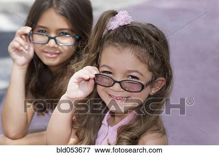 Stock Photo - Hispanic sisters wearing eyeglasses. Fotosearch