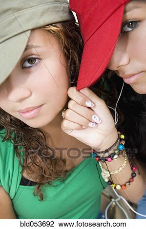 Stock Image - Hispanic teenaged girls wearing hats. Fotosearch