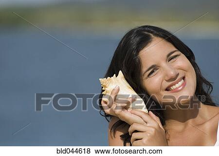 Hispanic woman listening to seashell View Large Photo Image Stock Photo - Hispanic woman listening to seashell. Fotosearch