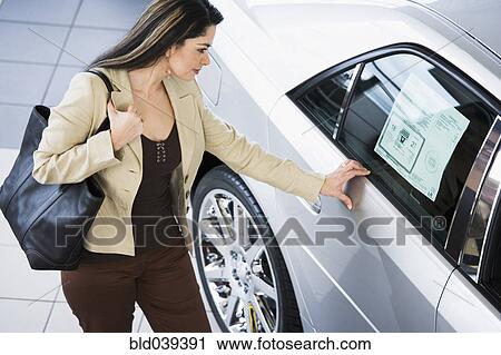 Stock Image - Hispanic woman looking at new car. Fotosearch