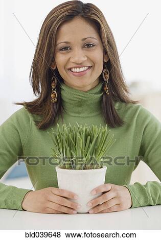 Stock Photo - Indian woman holding potted plant. Fotosearch
