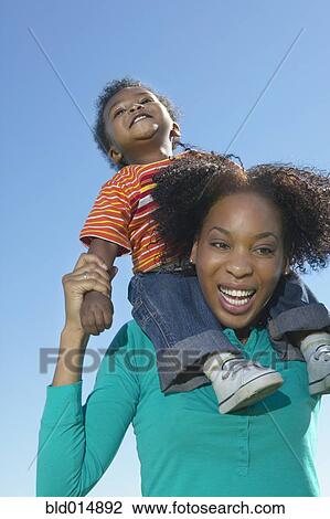 Low angle view of woman with young son on shoulders View Large Photo Image Stock Image - Low angle view of woman with young son on shoulders. Fotosearch