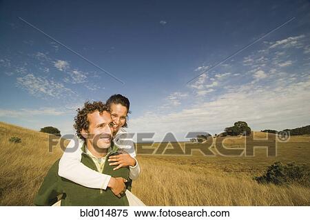 Stock Photography - Man giving woman piggy back ride. Fotosearch