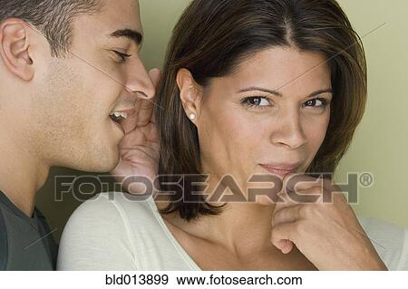 Stock Photo - Man whispering into woman's ear. Fotosearch
