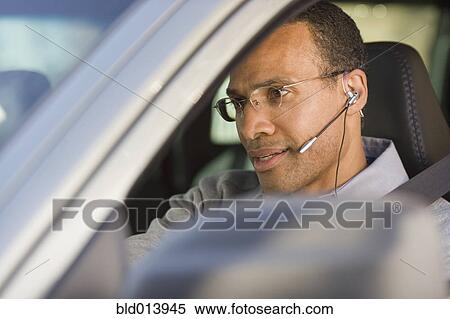 Stock Photography - Man with earpiece in car. Fotosearch