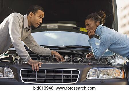Mechanic explaining to woman while leaning over car View Large Photo Image Stock Photograph - Mechanic explaining to woman while leaning over car. Fotosearch