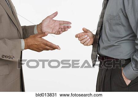 Stock Image - Mid section of two businessmen facing each other with hands gesturing. Fotosearch