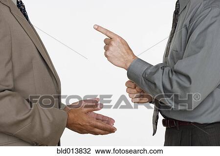 Stock Image - Mid section of two businessmen facing each other with hands gesturing. Fotosearch