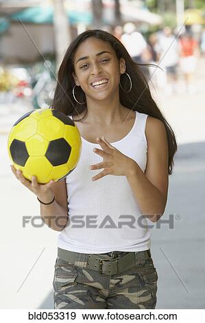 Mixed Race teenaged girl holding soccer ball View Large Photo Image Stock Photo - Mixed Race teenaged girl holding soccer ball. Fotosearch