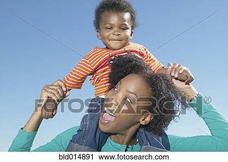 Mother holding young son on shoulders View Large Photo Image Stock Image - Mother holding young son on shoulders. Fotosearch