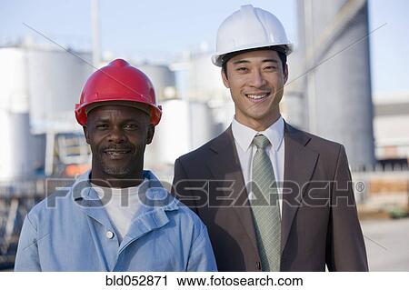 Stock Image - Multi-ethnic businessman and construction worker wearing hardhats. Fotosearch