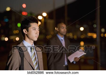 Stock Photograph - Multi-ethnic businessmen outdoors at night. Fotosearch