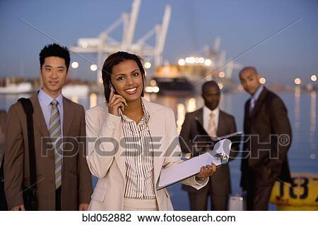 Stock Image - Multi-ethnic businesspeople in front of water. Fotosearch